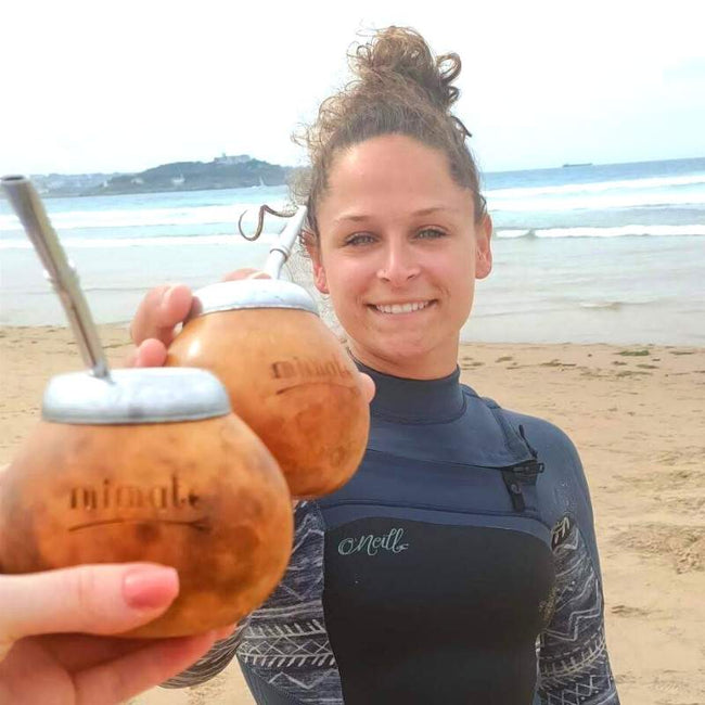 femme tenant une calebasse de maté traditionnelle à la plage